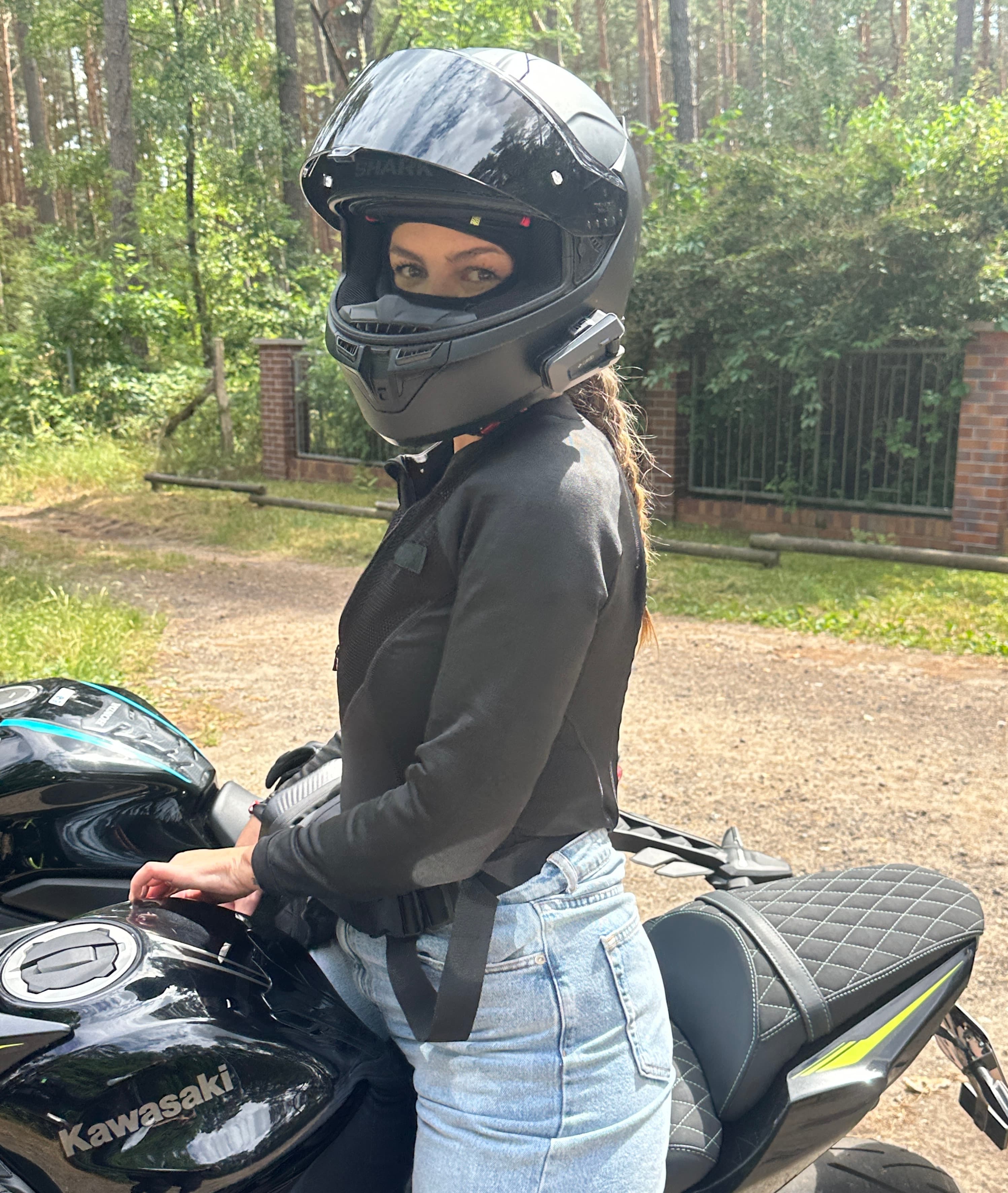 Motorradfahrer steht neben einer schwarzen Kawasaki auf einem malerischen Waldweg – plane entspannte Motorradtouren in schöner Landschaft mit unserer Motorradnavigation.